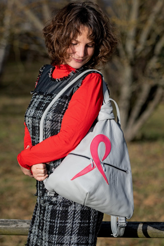 Pink Ribbon grey leather backpack wearing by a woman outside in the nature