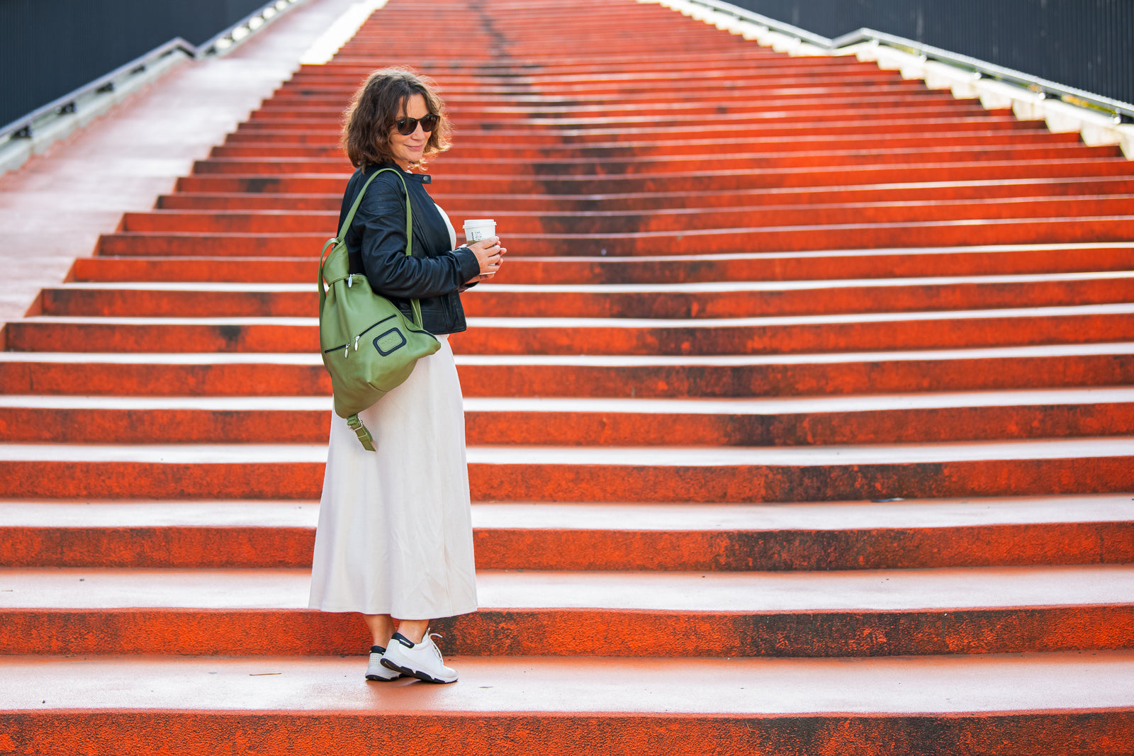 green leather backpack with a women on lon stairs