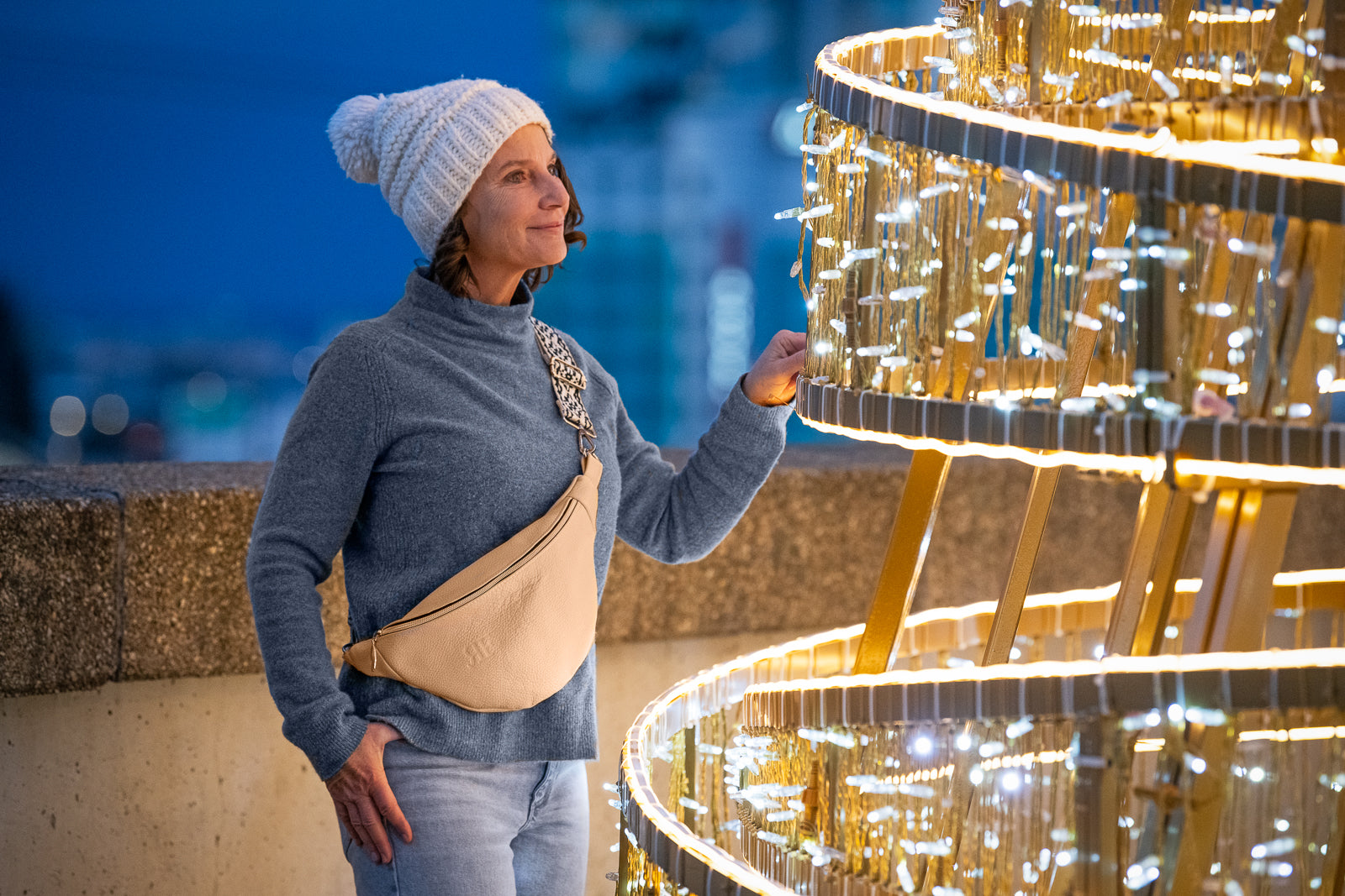 Woman in winter clothing standing next to a large, ornate golden structure.