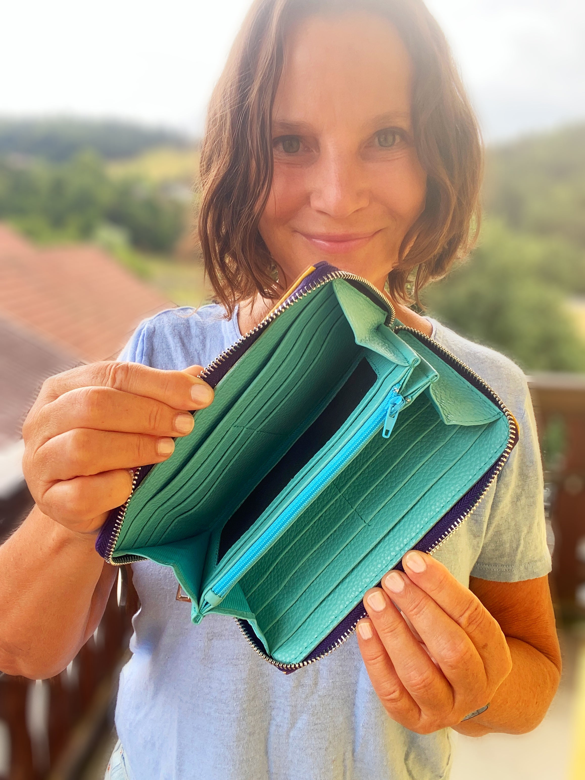 Person holding a green wallet with a scenic background