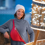 Woman wearing a gray sweater and white beanie with a red bag, standing next to a decorative light structure.