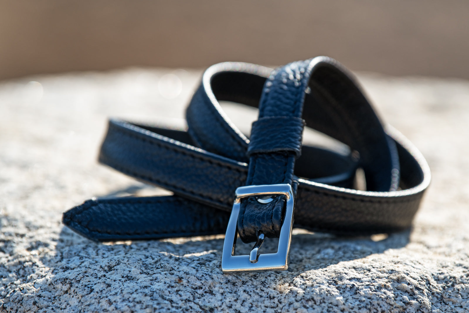 Blue leather belt with a silver buckle on a textured surface