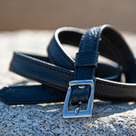 Blue leather belt with a silver buckle on a textured surface