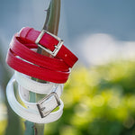 Red and white leather belts with silver buckles on a blurred natural background