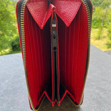 Red wallet with silver zipper on a textured surface