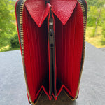 Red wallet with gold zipper on a textured surface