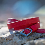 Red belt with a silver buckle on a stone surface with a blurred natural background