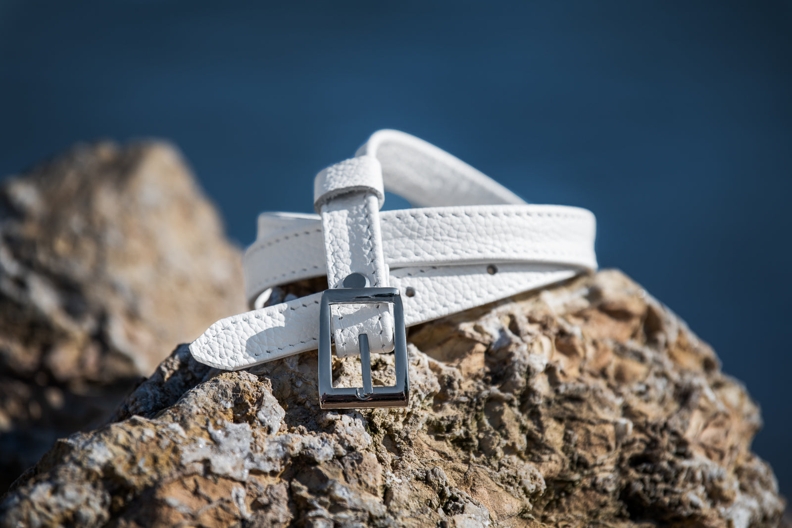 White belt with a silver buckle on a rocky surface