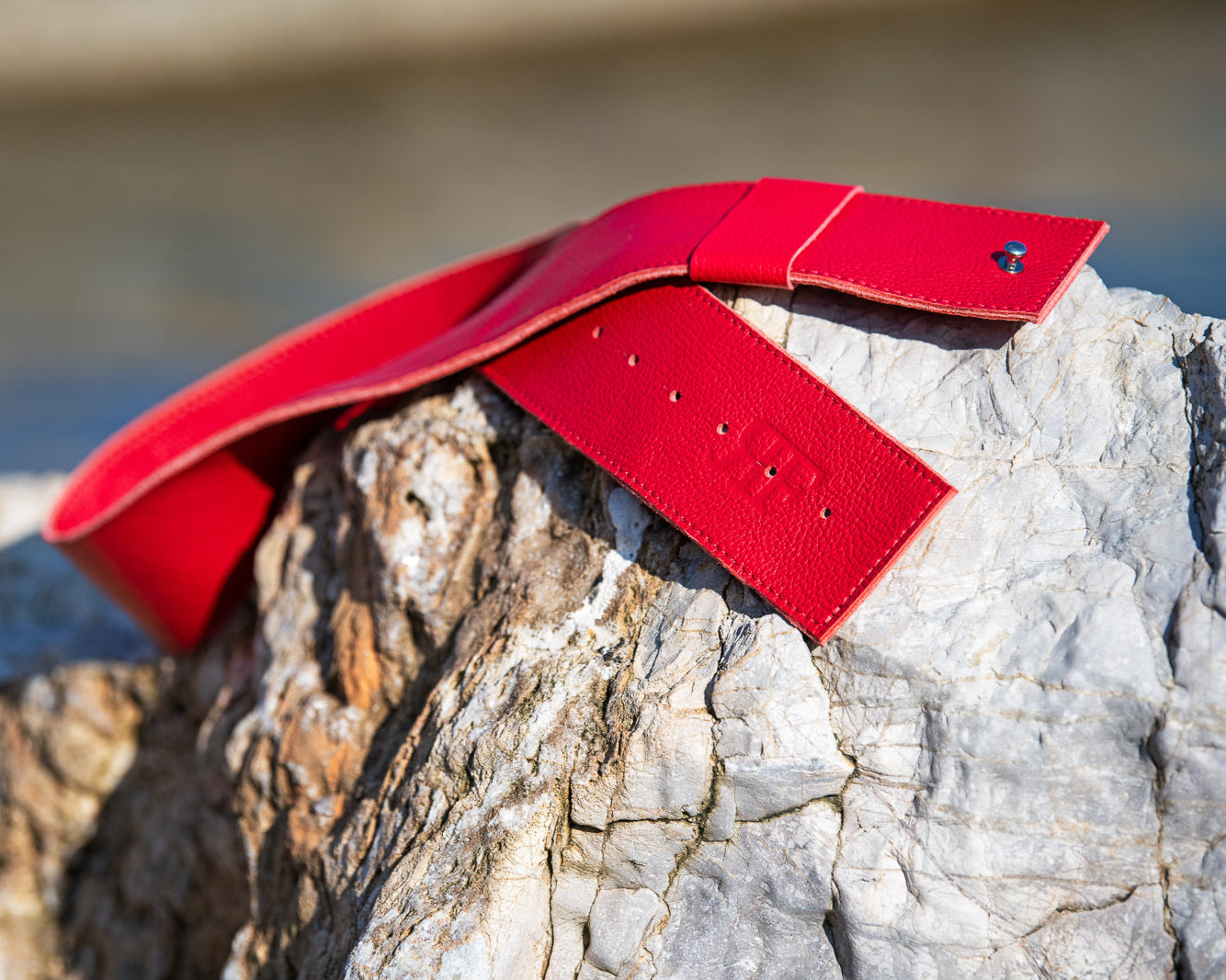 Red leather belt on a rock with a blurred natural background