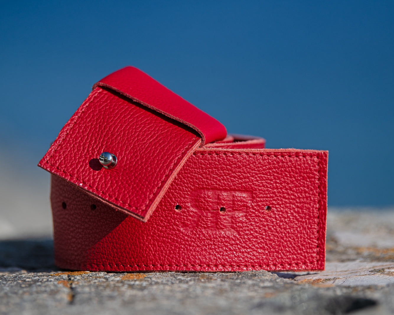Red leather wallet on a textured surface with a blue sky background