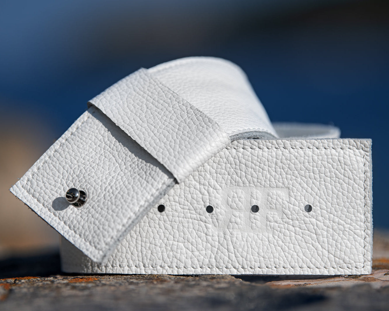 White leather wallet on a textured surface with a blurred blue background