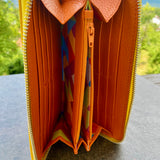 Open orange wallet with colorful interior on a gray surface